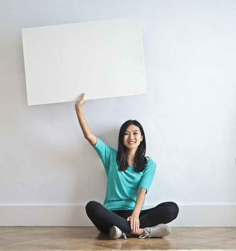 Smiling woman holding up a blank poster.